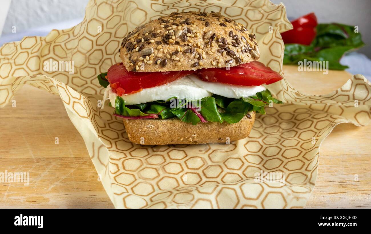 Bienenwachs-Verpackung für ein Lunch-Sandwich mit Brotbrötchen, Mozzarella-Käse und Salat. Nahaufnahme. Stockfoto
