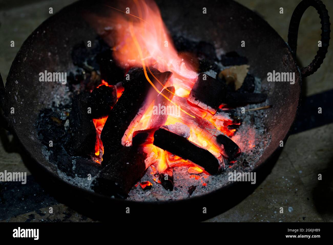 Verbrennung von Holzkohle in einem Eisenofen für die Heizung zu Hause. Rot verbrannte Holzkohle und Asche, um den Raum zu erwärmen. Stockfoto