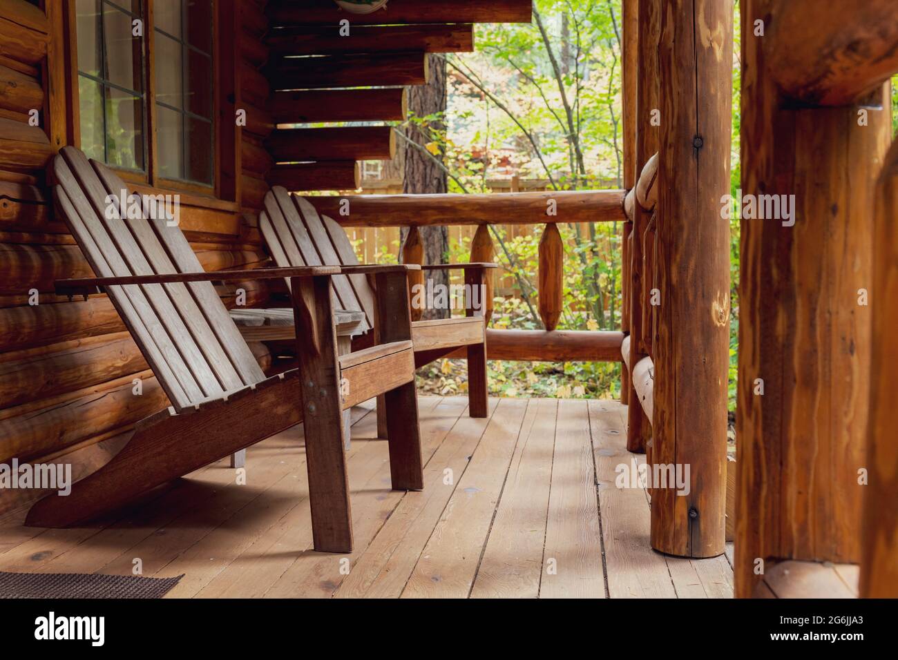 Veranda der rustikalen Blockhütte mit hölzernen Adirondack-Stühlen Stockfoto