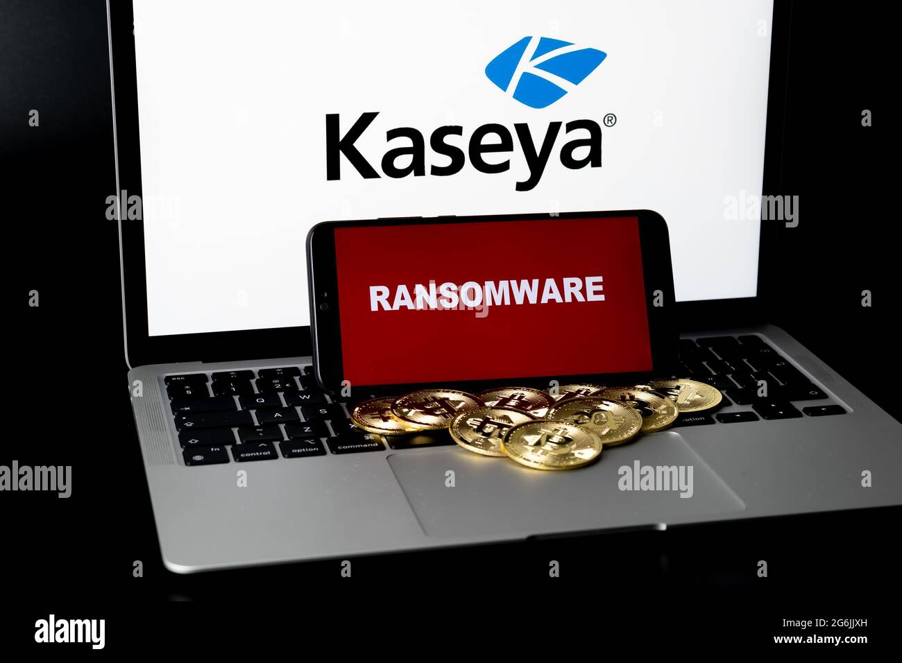Smartphone mit RANSOMWARE-Wörtern und unscharfen Bitcoins und Kaseya-Logo auf dem Laptop. Konzept für den Angriff auf die Software und Sicherheitsverstöße. Stafford, United Stockfoto