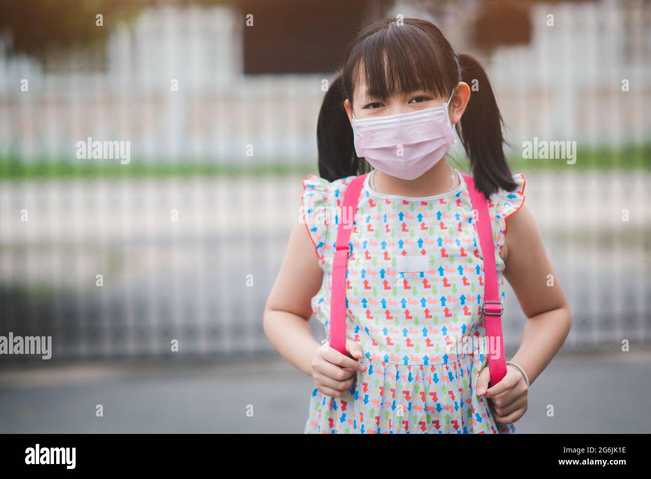 Portrait von asiatischen Mädchen tragen Rucksack und covid-19 Schutz Gesichtsmaske bereit für die Grundschule. Konzept des Rückens in die Schule Stockfoto