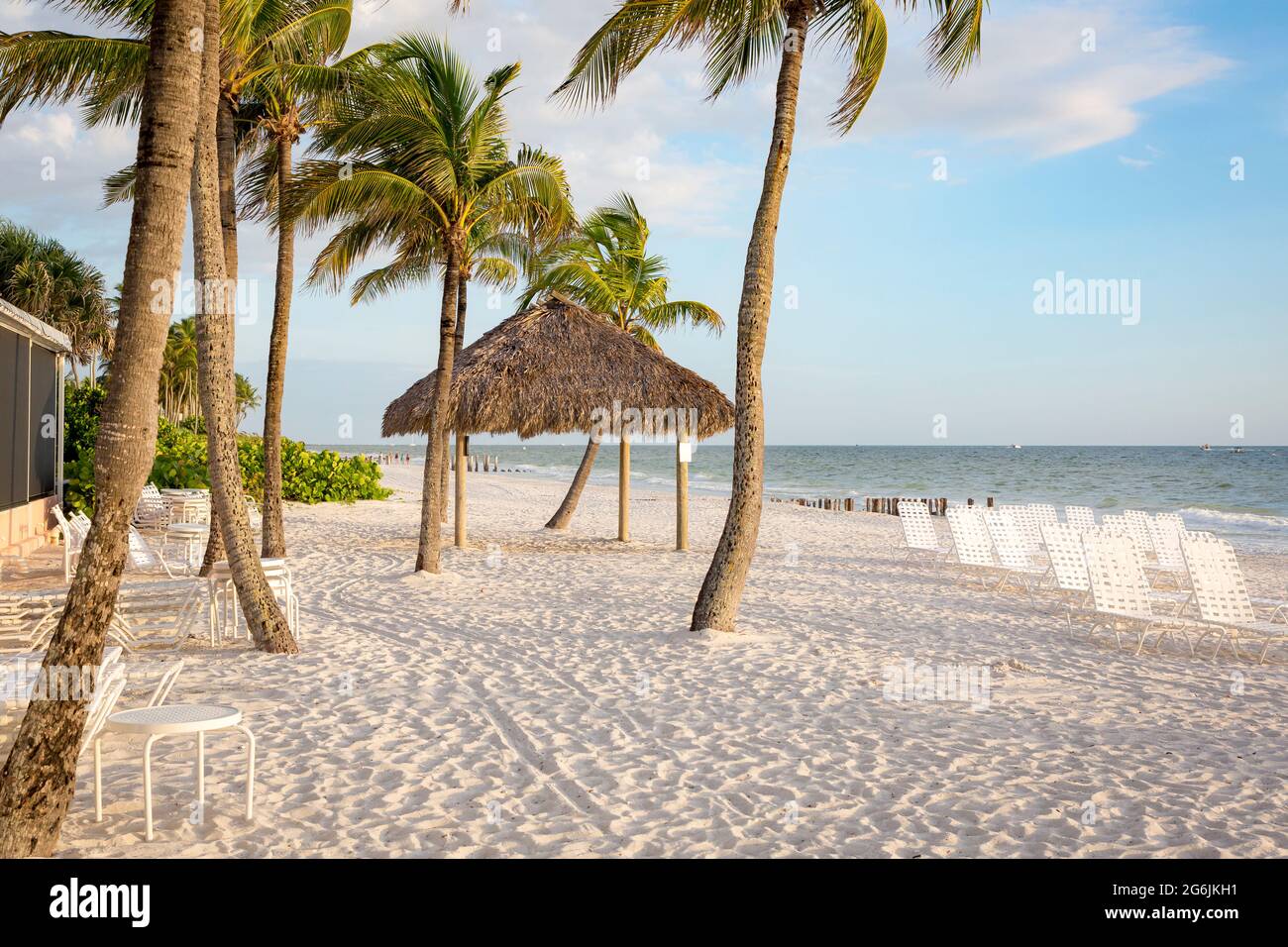 Strandliegen, grasüberdachte Hütte und Palmen am Strand in Naples, Florida, USA Stockfoto