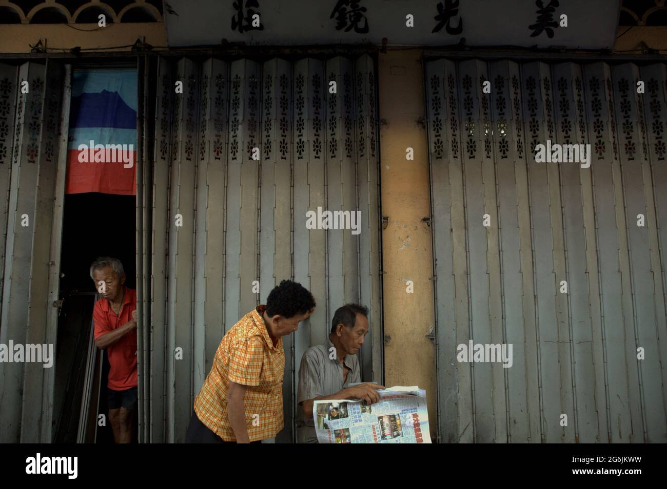 Ältere Bürger lesen Zeitung auf Gaya Sunday Market, Gaya Street, Kota Kinabalu, Sabah, Malaysia. Stockfoto