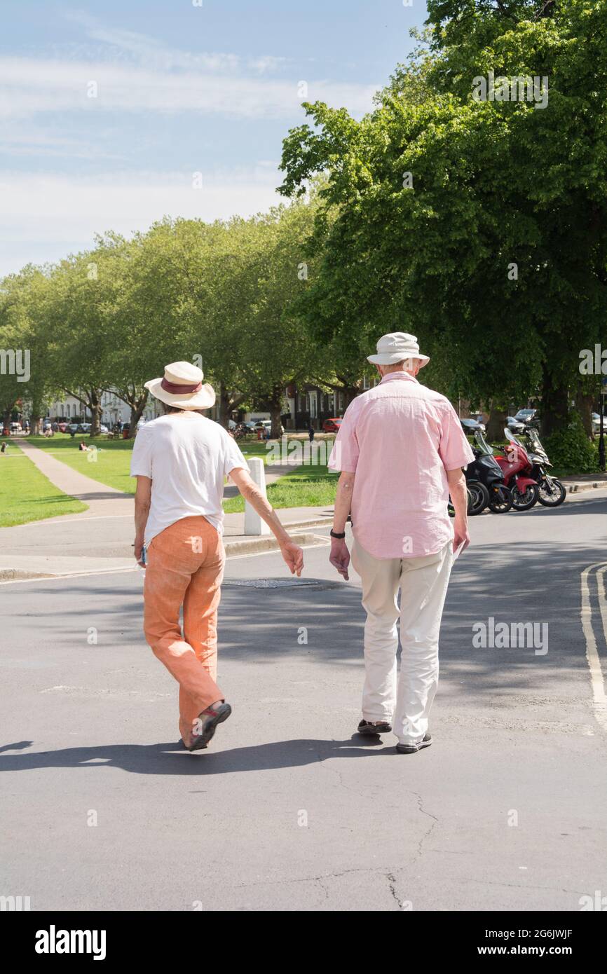 Ein älteres Paar, das zusammen auf Richmond Green, Richmond, Surrey, England, Großbritannien, läuft Stockfoto
