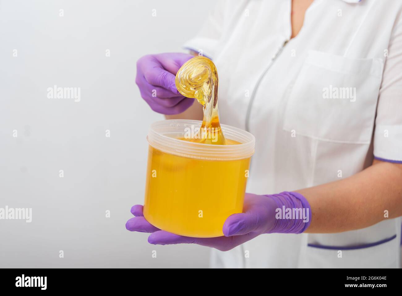 Natürliche Honigzucker-Paste shugaring Nahaufnahme. Frauen Kosmetikerin hält Glas Wachs aus Paste für Zucker Enthaarung shugaring, weißen Hintergrund Stockfoto