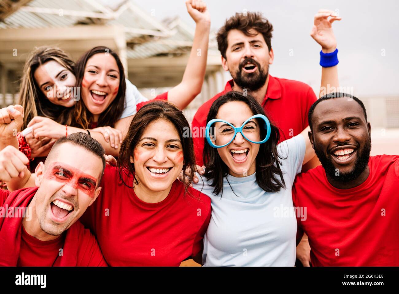 Multirassische Zuschauergruppe in Teamfarben beim Fußballschauen im Stadion Stockfoto