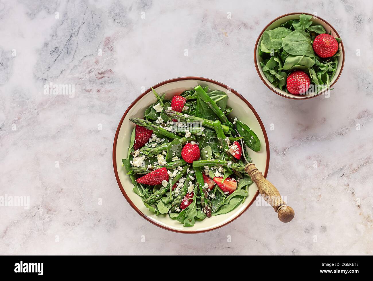 Frische Erdbeeren, grüner Spargel, Feta-Käse, Babyspinat und Rucola-Salat in einer Schüssel serviert. Saisonales Mittagessen, sauberes Essen, vegetarisches Essen. Top V Stockfoto