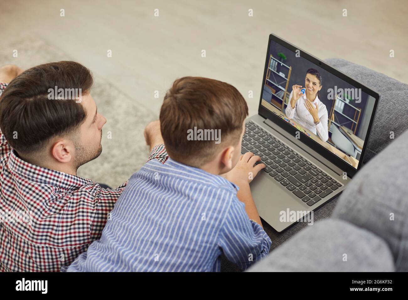 Vater und Sohn beim Online-Unterricht mit Englischlehrer auf dem Laptop Stockfoto