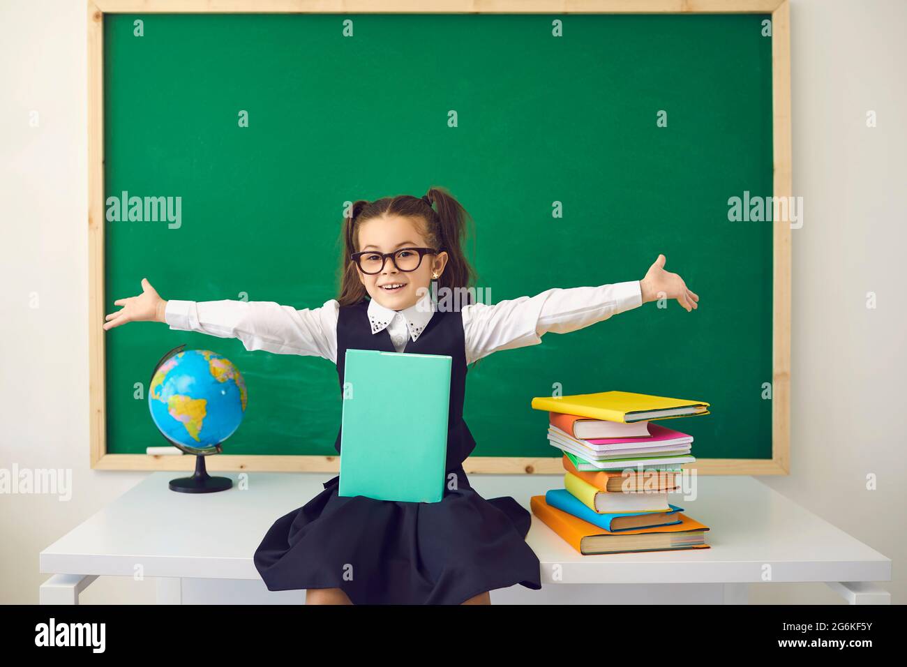 Zurück zum Schulkonzept. Schulmädchen mit Brille lächelt im Klassenzimmer mit einer Schultafel. Stockfoto