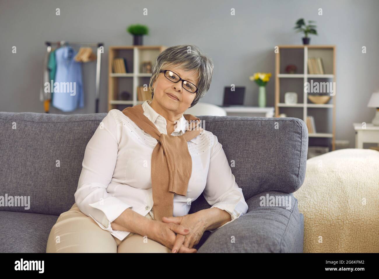 Selbstbewusste, stilvolle ältere, ältere Frau mittleren Alters sitzt im Heimbüro auf dem Sofa Stockfoto