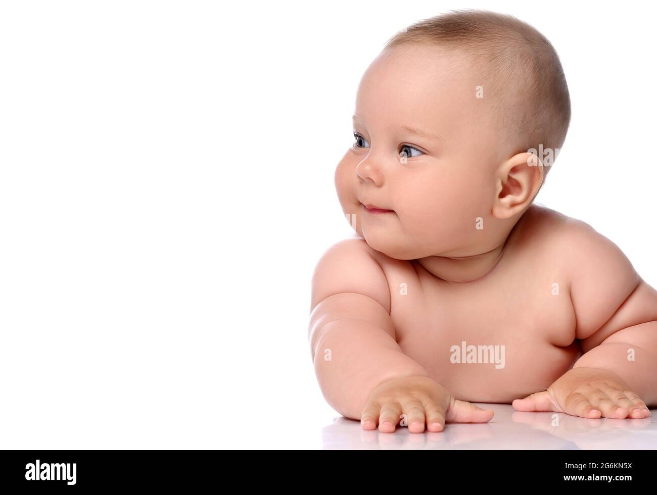 Fokussiertes Kleinkind Baby Baby Mädchen Kind in Windel liegt auf ihrem Bauch und schaut aufmerksam beiseite Stockfoto
