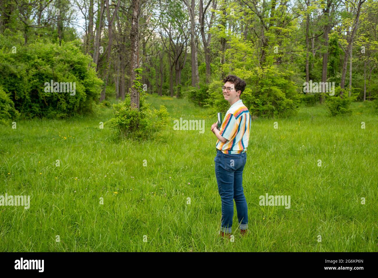 Fröhliche Person allein im Freien in der Natur mit einem Buch Stockfoto