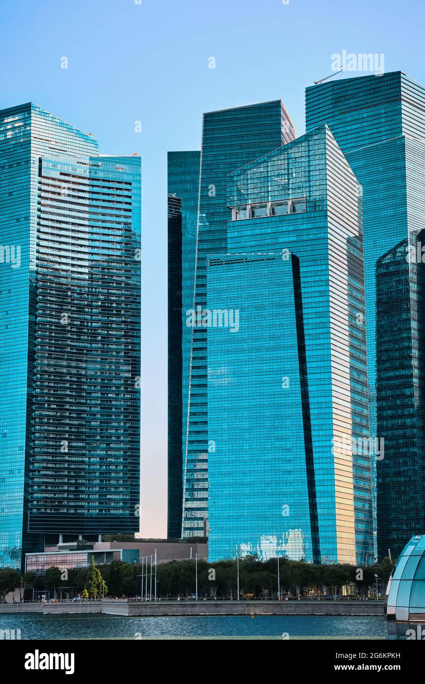 Gruppe von Gebäuden im CBD oder zentralen Geschäftsviertel über Marina Bay Waters im Tageslicht, Singapur. Vertikale Aufnahme in Cyan-Farben. Stockfoto