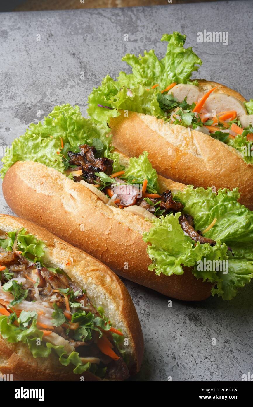 Ein köstliches Bánh Mì-Sandwich gefüllt mit herzhaftem Schweinefleisch, frischen Kräutern und eingelegtem Gemüse, serviert in einem knusprigen Baguette – ein perfekter Geschmack von Vietnamesisch Stockfoto