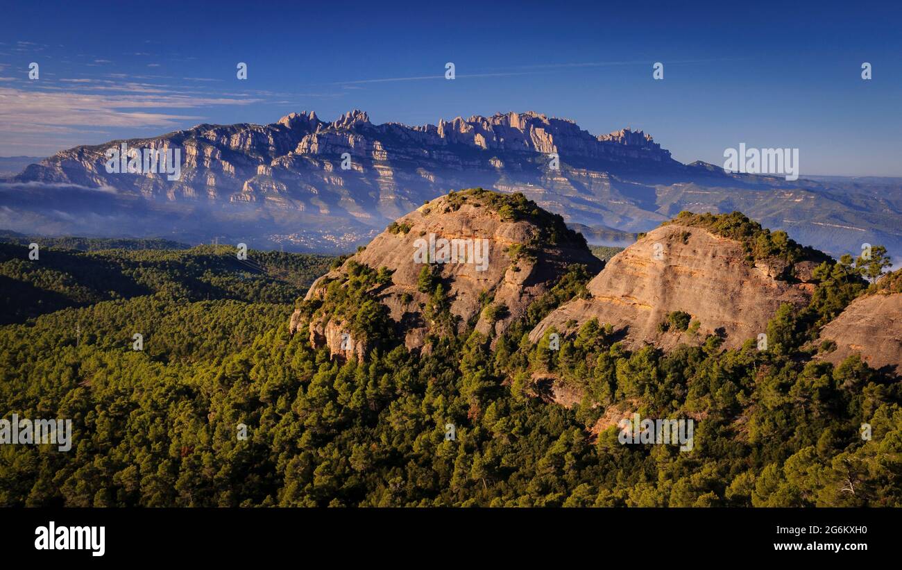 Montserrat und im Vordergrund einige Felsen des Naturparks Sant Llorenç del Munt i l'Obac (Barcelona, Katalonien, Spanien) Stockfoto