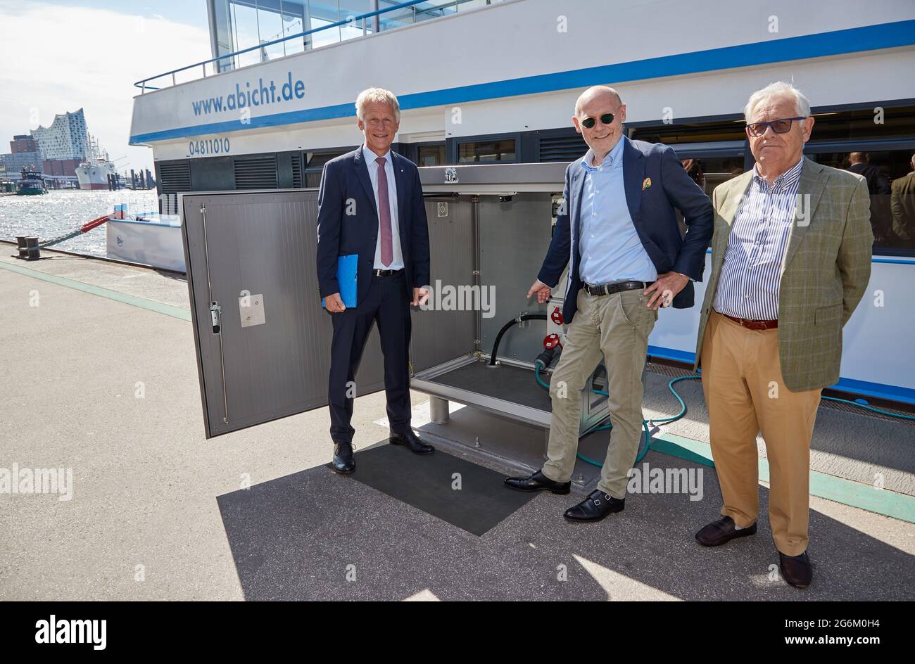 07. Juli 2021, Hamburg: Jens Meier (l), Vorsitzender des Vorstands der Hamburger Hafenbehörde (HPA), Michael Westhagemann (non-Party), Wirtschaftssenator, Und Rainer Abicht, Reeder, steht bei einer Presseveranstaltung an den Landungsbrücken anlässlich der Einweihung des ersten Landkraftwerks für die Binnenschifffahrt neben einer Strombox. Mit der Einweihung des Landkraftwerks an den Hamburger Landungsbrücken wurde die erste der geplanten Landkraftanlagen für die Binnenschifffahrt im Hamburger Hafen eröffnet. Das Landstromanlage wird es geben Stockfoto