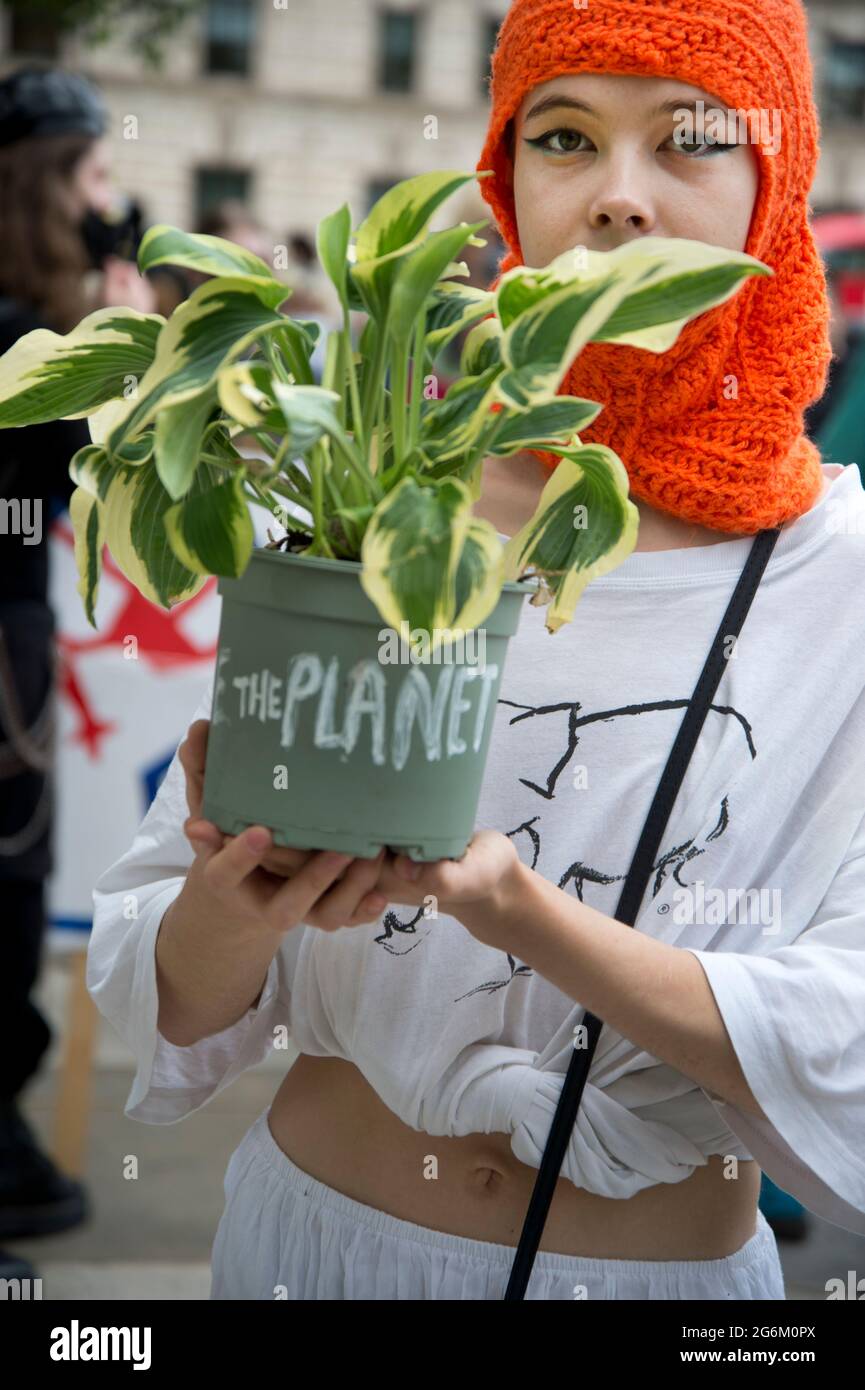 Westminster, London. Tötet die Bill-Kundgebung und Demonstration. Eine junge Frau, die eine orangefarbene Balaklava trägt, hält eine Pflanze mit dem Label 'Planet'. Stockfoto