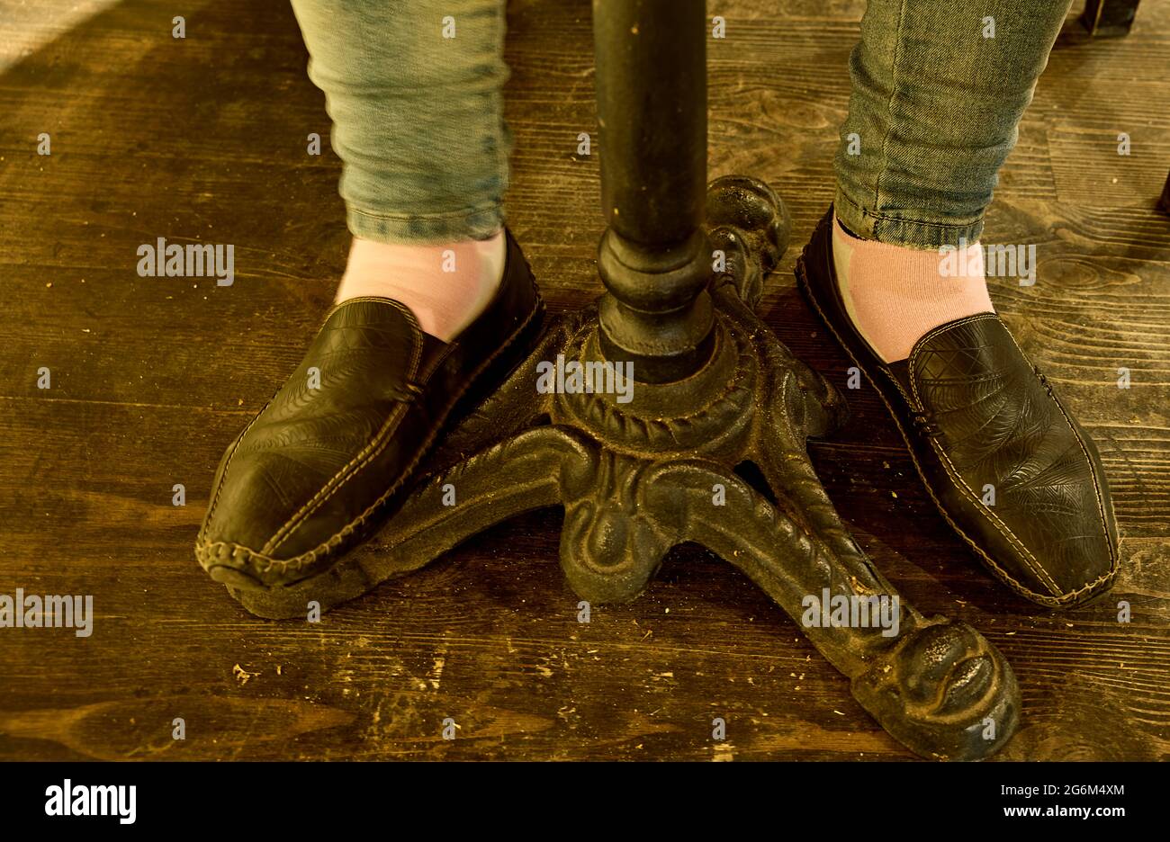 Frauenbeine in schwarzen Schuhen unter dem Tisch. Nahaufnahme, Tageslicht. Stockfoto