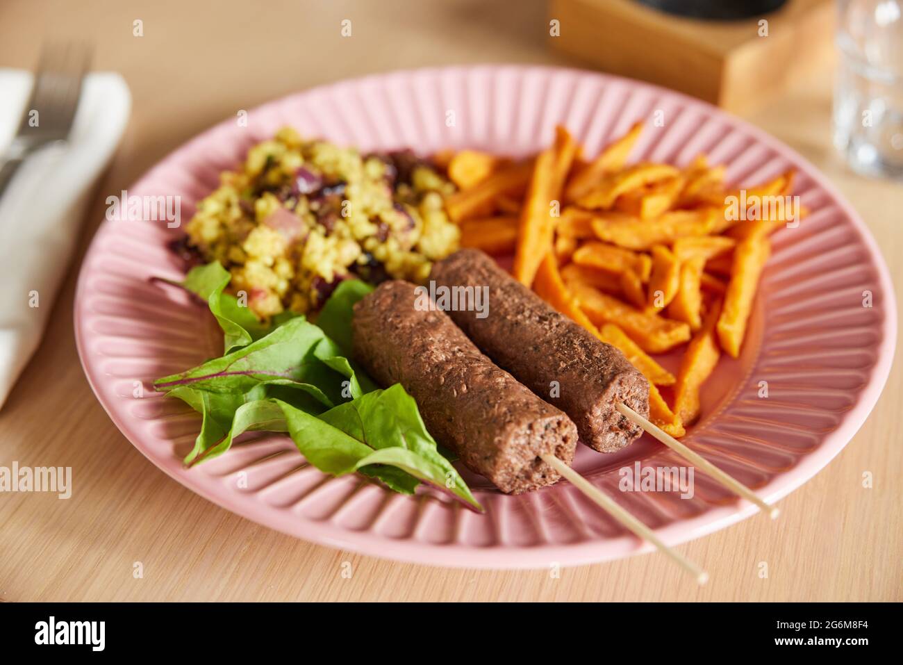 Veganes Gericht Auf Dem Teller Mit Kofta-Kebabs Auf Pflanzlicher Basis Mit Süßkartoffeln Und Couscous Und Salat Stockfoto