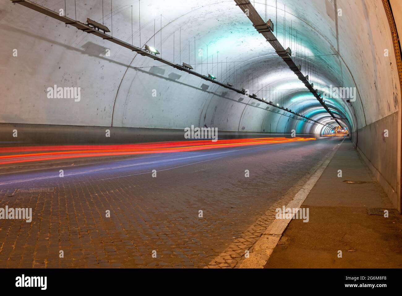 Lange Belichtung des Inneren eines künstlich beleuchteten Verkehrstunnels Rücklicht Streifen sind zu sehen Stockfoto