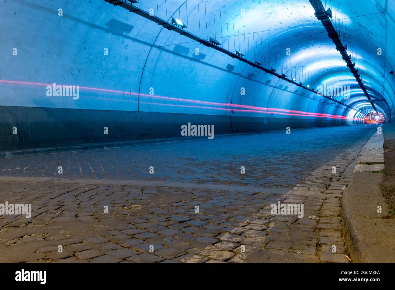 Lange Belichtung des Inneren eines künstlich beleuchteten Verkehrstunnels Rücklicht Streifen sind zu sehen Stockfoto