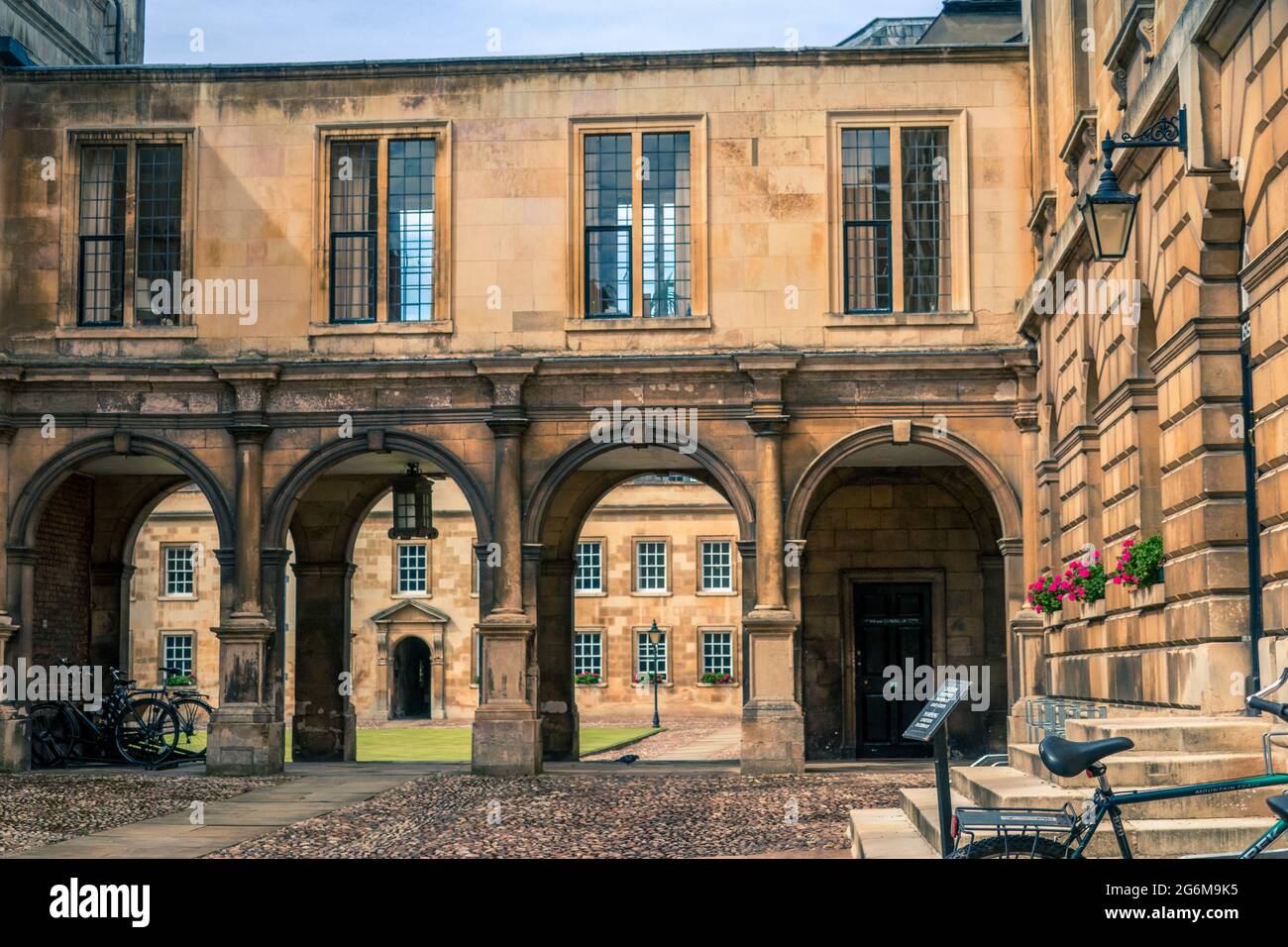 First Court of Peterhouse College University of Cambridge mit gewölbtem Gehweg mit Galerien oben und Zyklen im Vordergrund auf gepflastertem Boden Stockfoto
