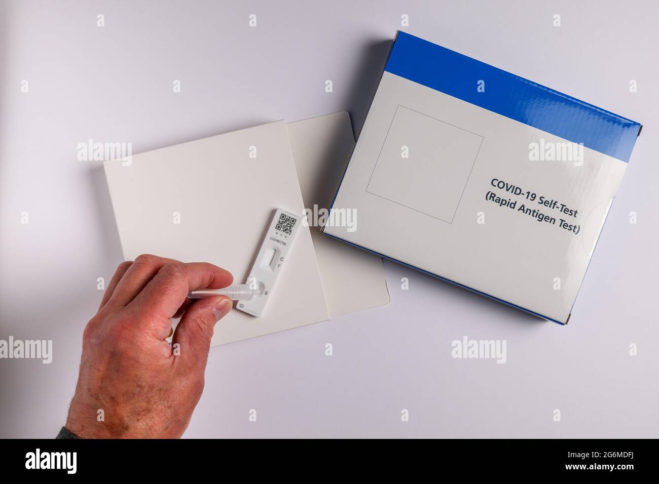 Coronavirus Covid-19 Lateral-Flow-Selbsttest-Kit mit männlicher Hand auf weißem Hintergrund Rapid Antigen Test-Kit Stockfoto