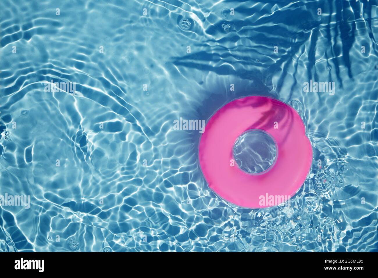 Pink Pool Float Ring schwimmt in einem erfrischenden blauen Pool. Draufsicht Stockfoto