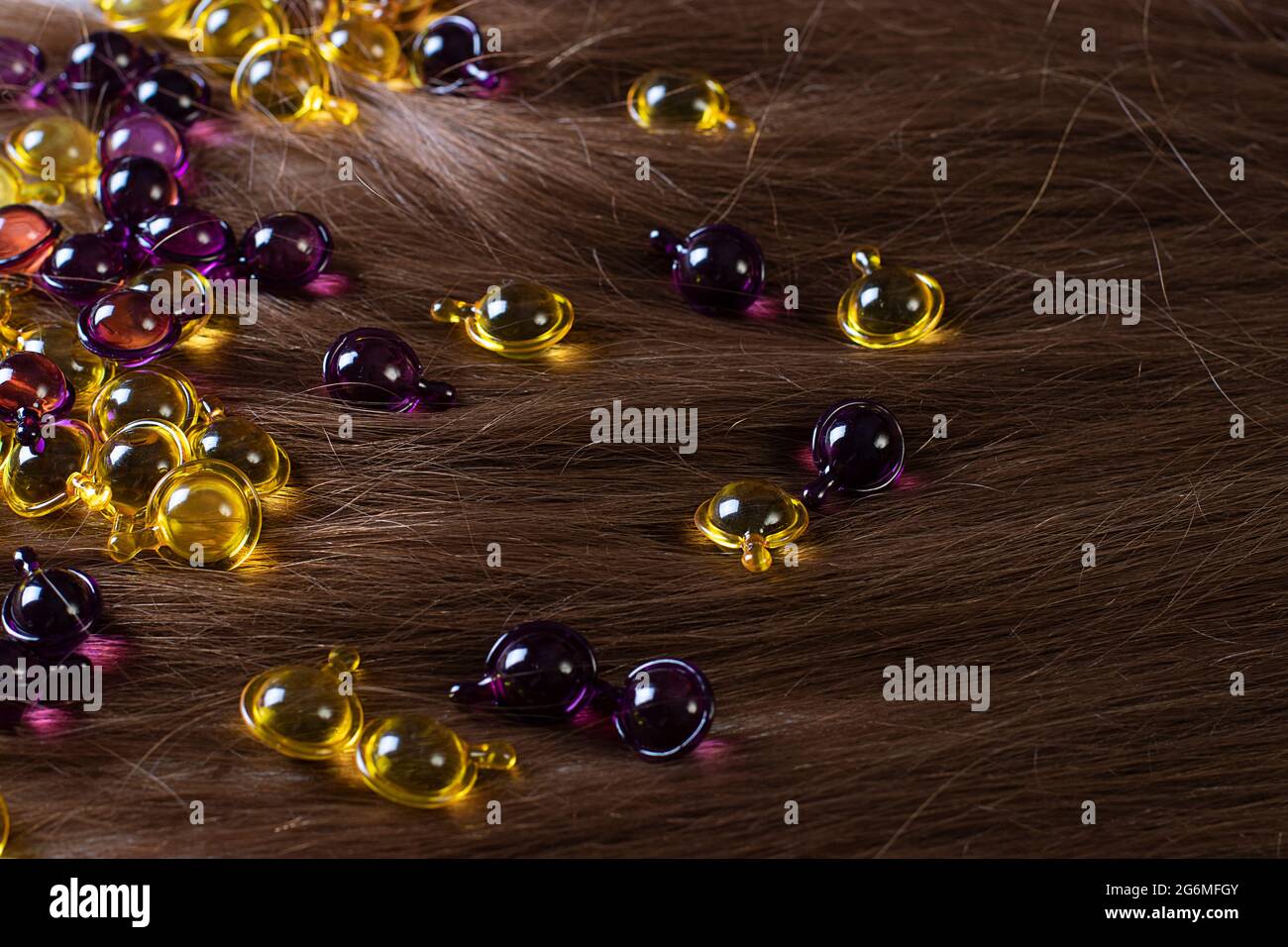 Haar Vitamin-Kapseln liegen auf braunem Haar: Haarbehandlung und Pflegeprodukte mit Öl für geschädigtes, hervorgehobenes, Dauerlicht und gefärbtes Haar Stockfoto