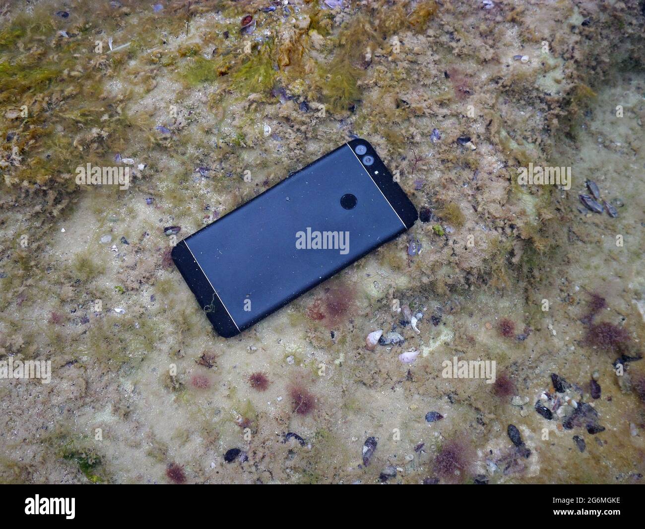 Smartphone unter Wasser. Beschädigtes Smartphone ertrank im Meer. Stockfoto