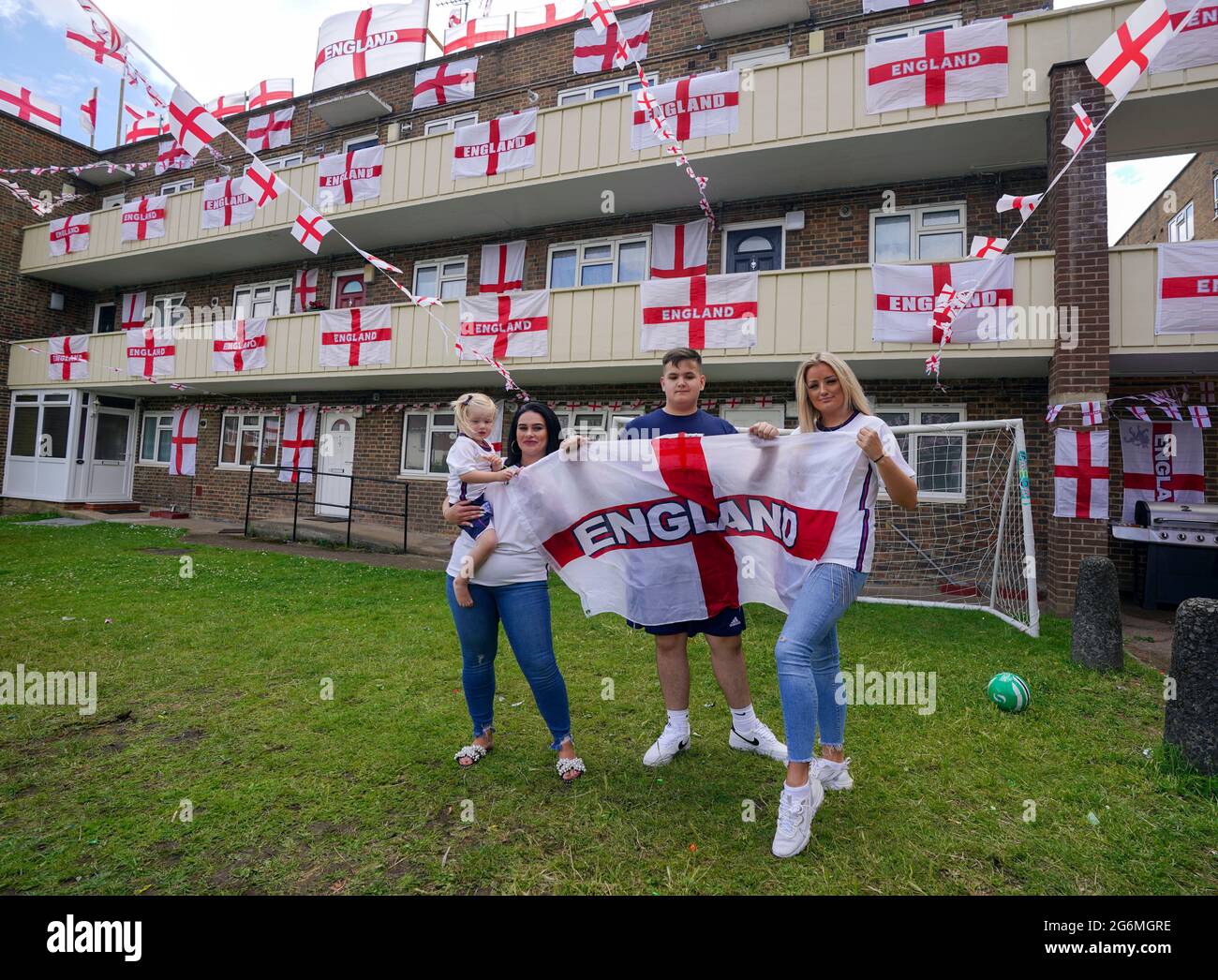 (Von links nach rechts) der zweijährige Dollie (Nachname nicht angegeben), Jade Brooks, Lewis Hickey und China Collis, einige der Bewohner von Towfield Court in Feltham, die ihr Anwesen mit englischen Flaggen für das Euro 2020-Turnier umgestaltet haben. Bilddatum: Mittwoch, 7. Juli 2021. Stockfoto