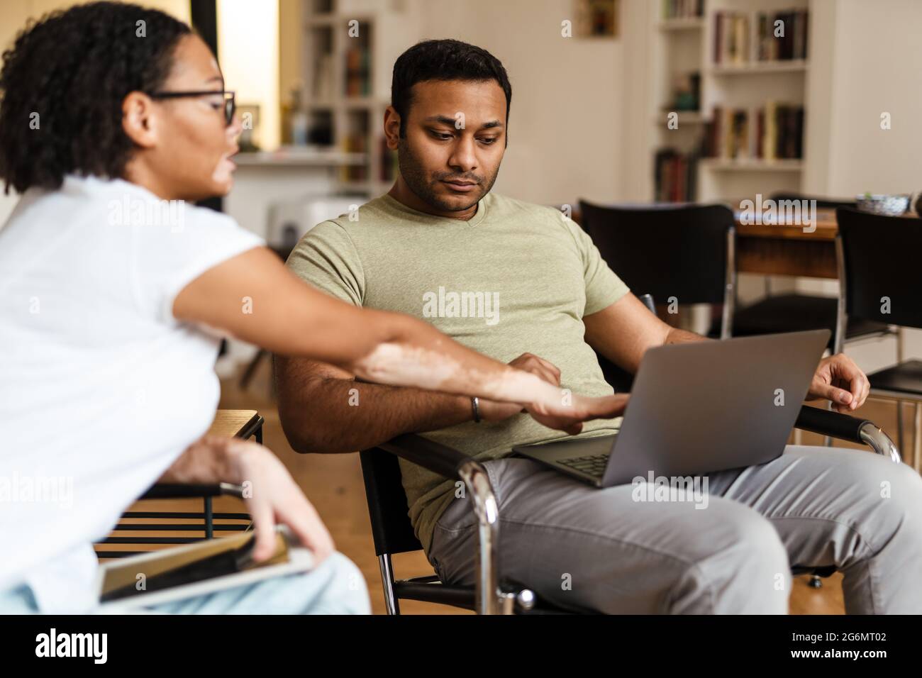 Mann und Frau aus dem Nahen Osten sprechen, während sie zu Hause mit einem Laptop und Tablet arbeiten Stockfoto
