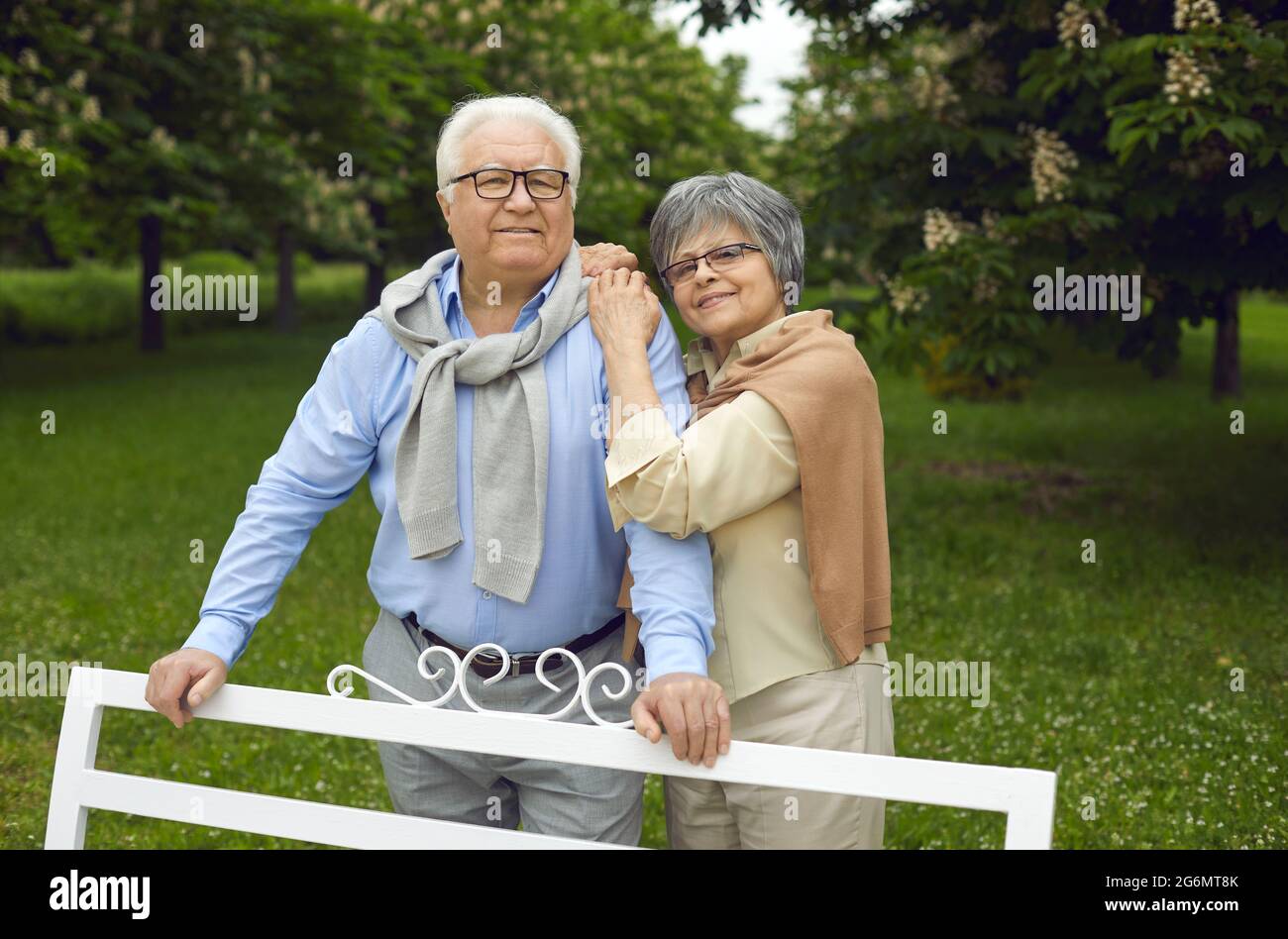 Glücklicher älterer Mann und Frau stehen an der Parkbank, Stockfoto