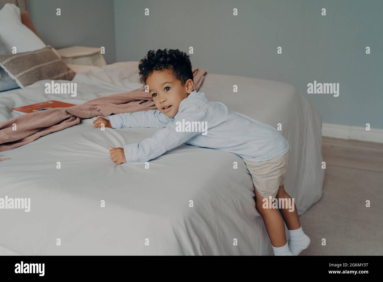 Süßer kleiner afroamerikanischer Junge, der zu Hause im gemütlichen Schlafzimmer spielt Stockfoto