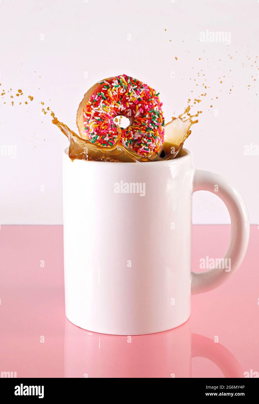 Donut spritzt in einer riesigen Tasse schwarzen Kaffee Stockfoto