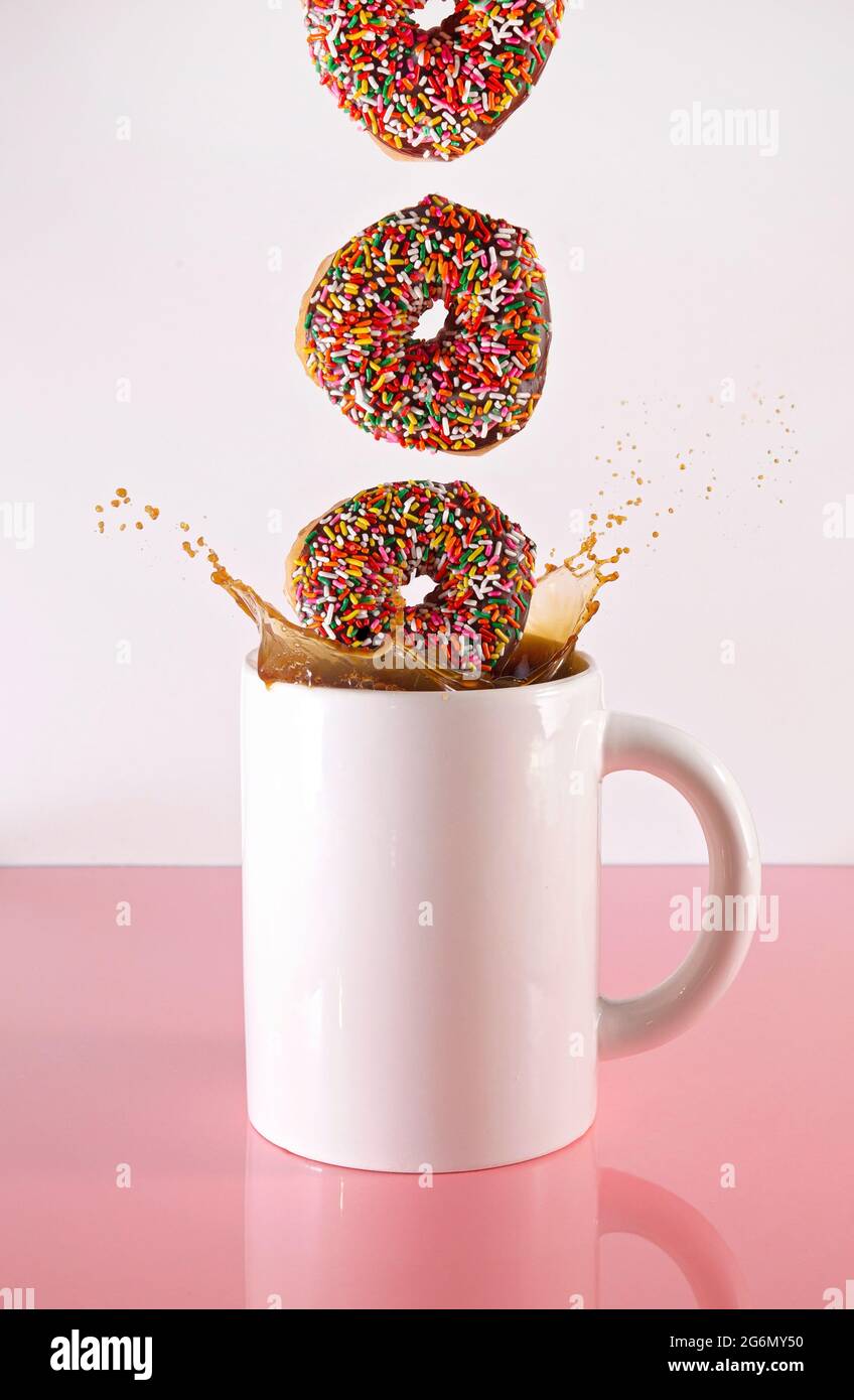 Donut spritzt in einer riesigen Tasse schwarzen Kaffee Stockfoto