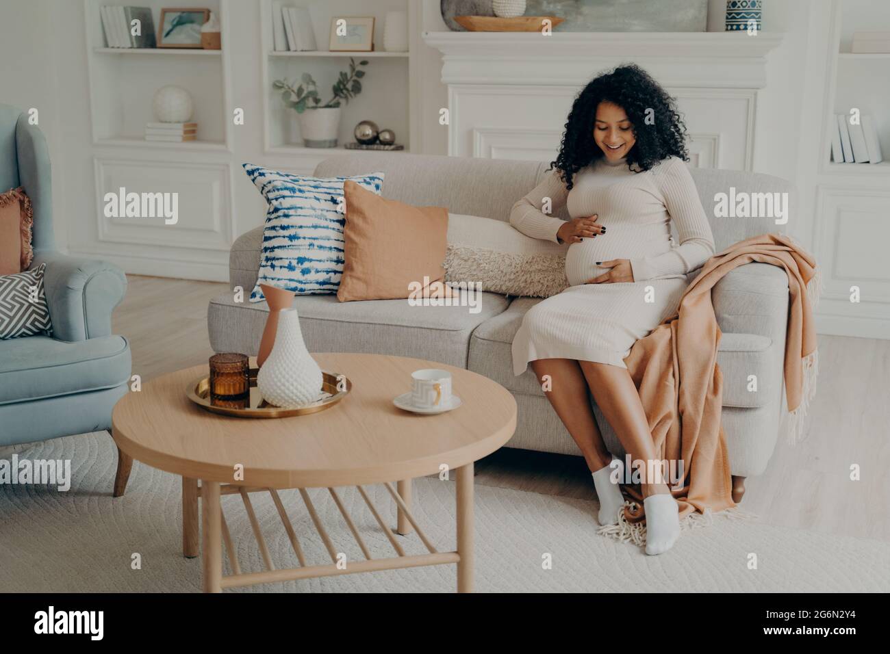 Schwanger afro amerikanische Frau sitzt auf der Couch und verbringt Zeit zu Hause Stockfoto