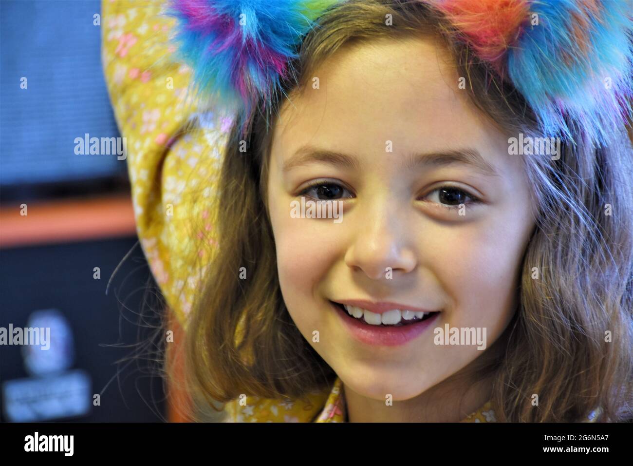 8-jähriges kaukasisches Mädchen mit braunen Augen und ihrem winzigen Hund und Farbtupfer im Haar lächelnd und eine schöne Zeit zu haben Stockfoto