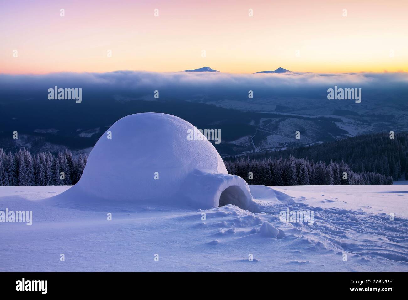 Iglu das Haus des isolierten Touristen steht auf einem hohen Berg weit weg vom menschlichen Auge. Fantastischer Wintersonnenaufgang. Wunderschöne, riesige, weiß verschneite Hütte. Stockfoto