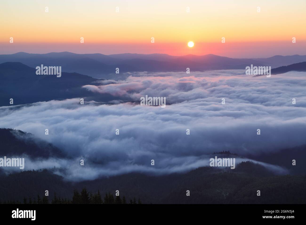 Der frühe Morgennebel. Majestätischer Frühlingstag. Eine schöne Landschaft mit hohen Bergen, Sonnenuntergang und Himmel mit Wolken. Dichter Nebel mit schönem Licht. Th Stockfoto