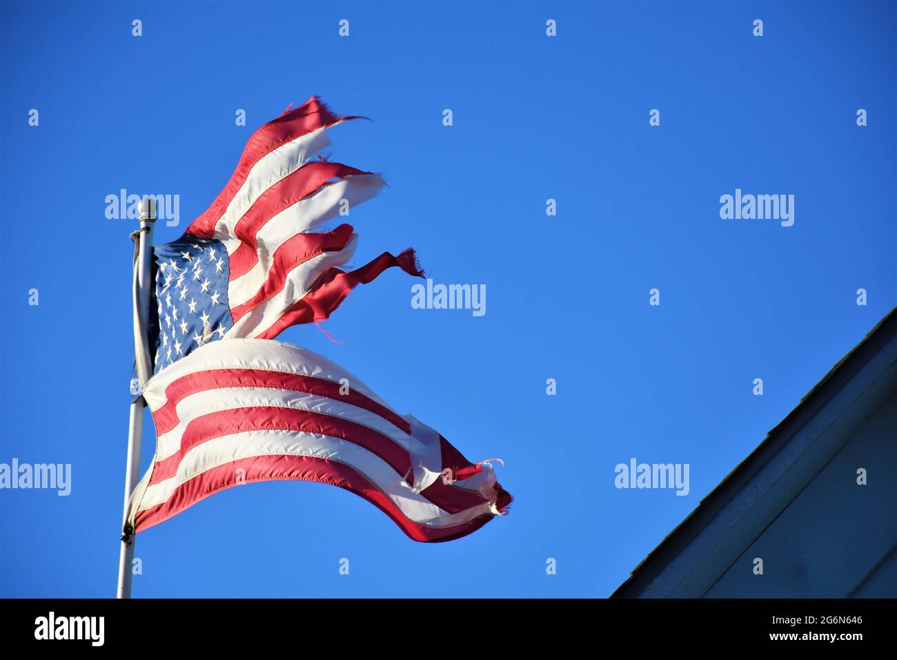 Der Wind hat diese amerikanische Flagge zerstört und muss wegen der Schäden durch Wind in Zentralkalifornien in einem Privathaus auf dem Bauernhof ersetzt werden Stockfoto