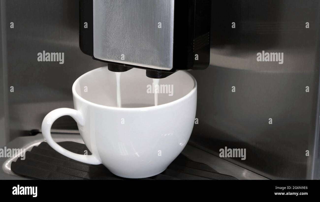 Vollautomatische Espressomaschine, die Milch in die Kaffeetasse gießt. Stockfoto