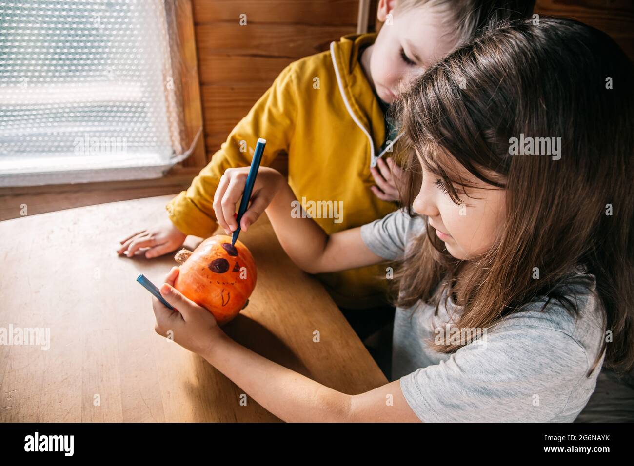 Niedliche Kinder Geschwister malen den halloween Kürbis zu Hause. Authentisches Leben. Stockfoto