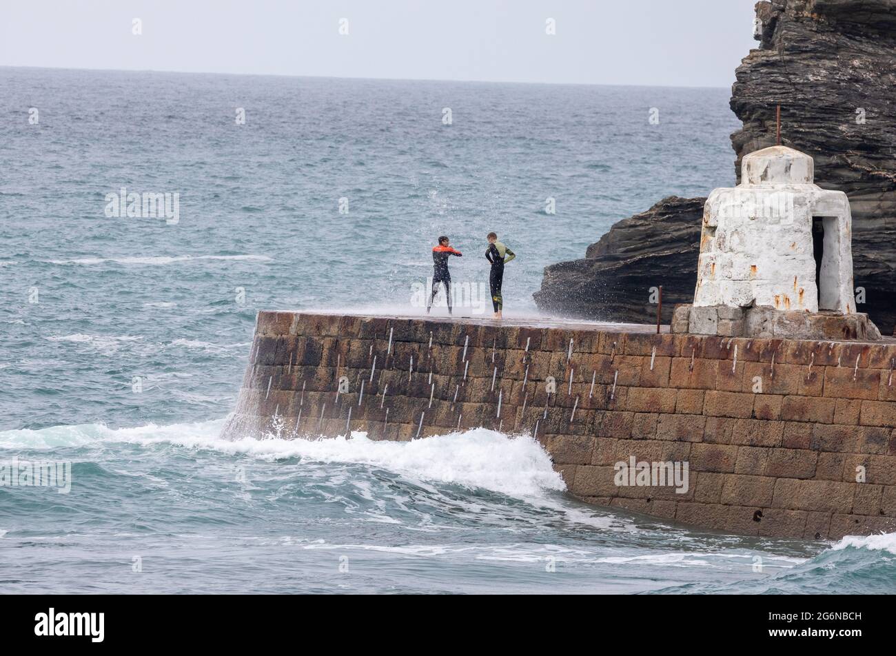 Portreath,Cornwall,7. Juli 2021,zwei Teenager stehen bei Flut in Portreath, Cornwall, gefährlich auf der Meeresmauer. Dies ist ein gefährlicher Ort, da oft extrem hohe Wellen darüber krachen, die eine Person ins Meer stoßen können. Kredit: Keith Larby/Alamy Live Nachrichten Stockfoto