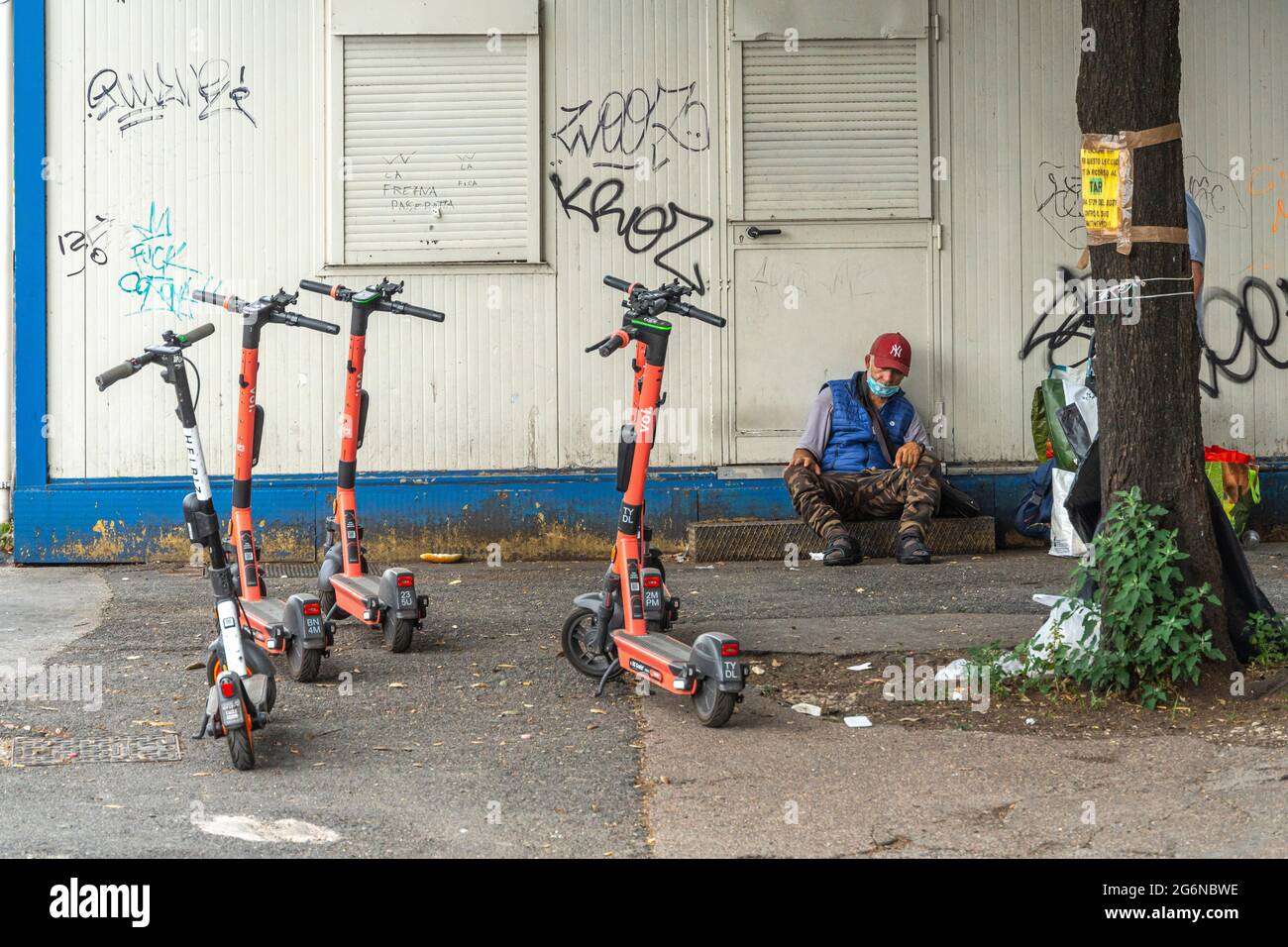 Parkplatz für Elektroroller. Obdachlose mit Maske, die auf der Straße schläft. Rom, Latium, Italien, Europa Stockfoto
