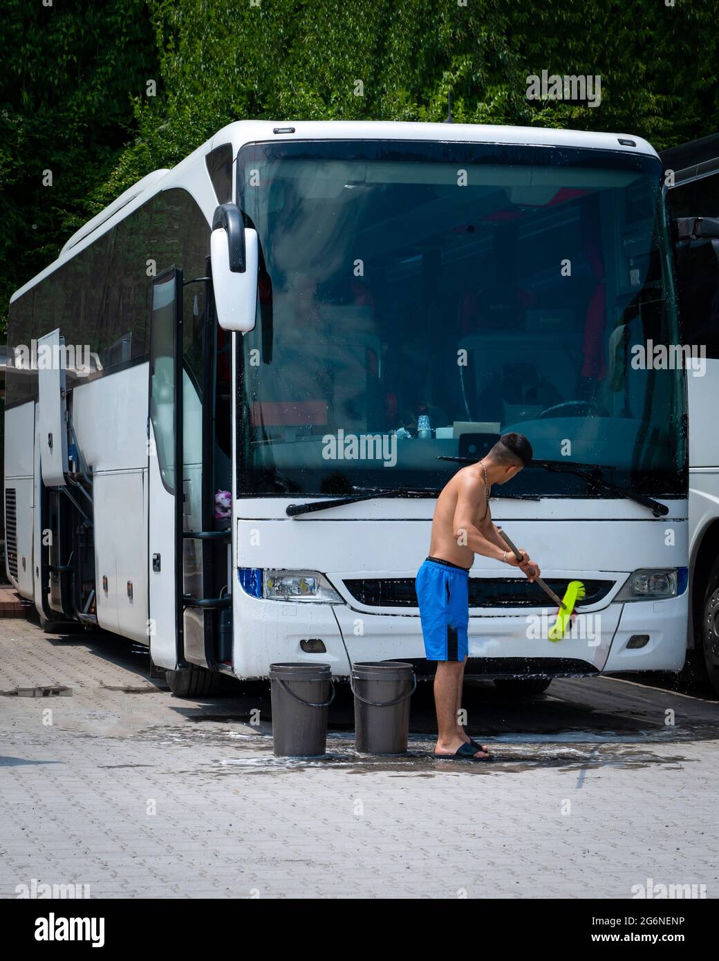 Mann wäscht Bus mit Pinsel Stockfoto
