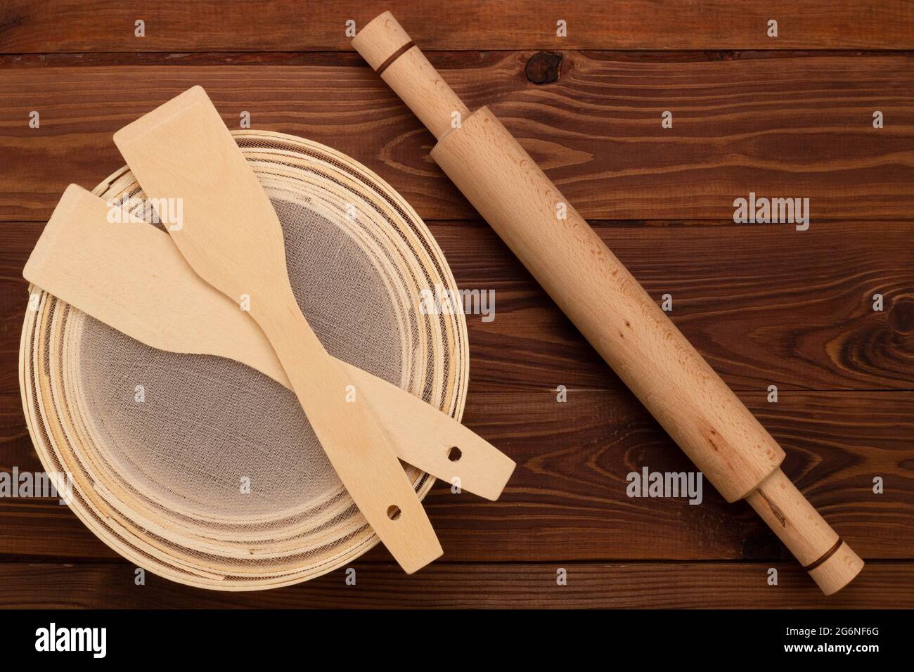 Antikes traditionelles Mehlsieb aus Buchenholz und feinem Drahtgeflecht, Teigrohling und kulinarischen Spateln auf braunem Hintergrund. Set für Sifti Stockfoto