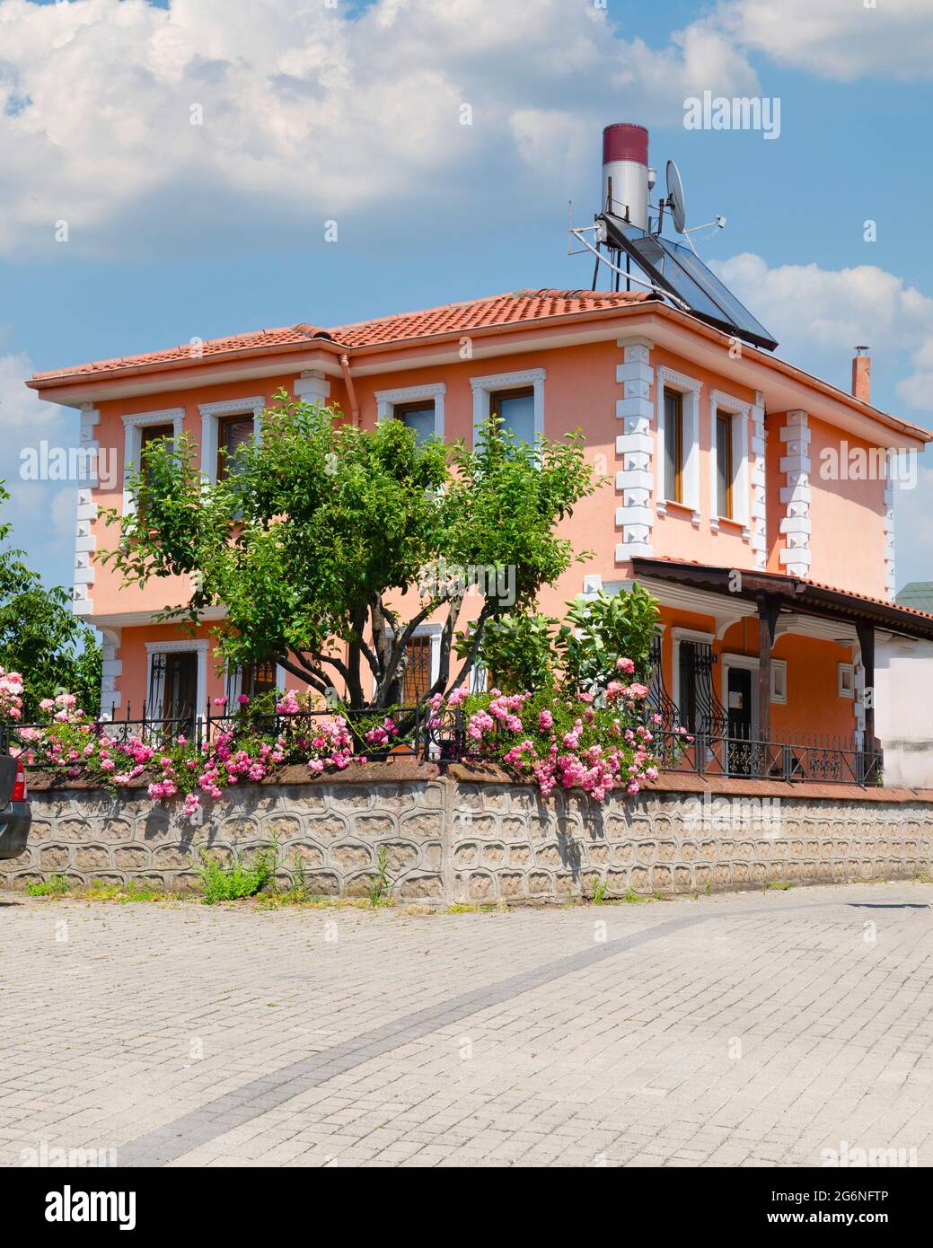 Rosafarbenes klassisches türkisches Haus, in dem Rosen in seinem Garten angebaut werden. Stockfoto