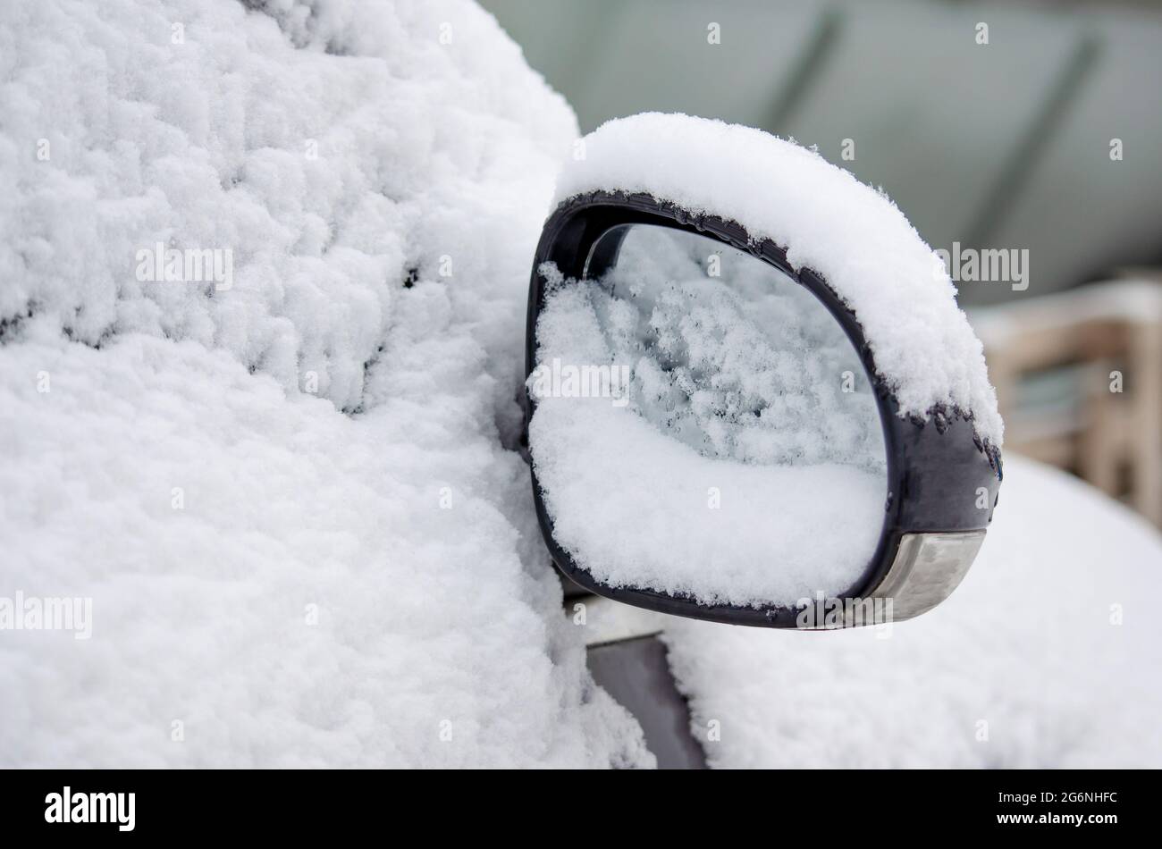 Gefrorener Rückspiegel, verschneites Auto. Winterschnee Schneefall. Stockfoto