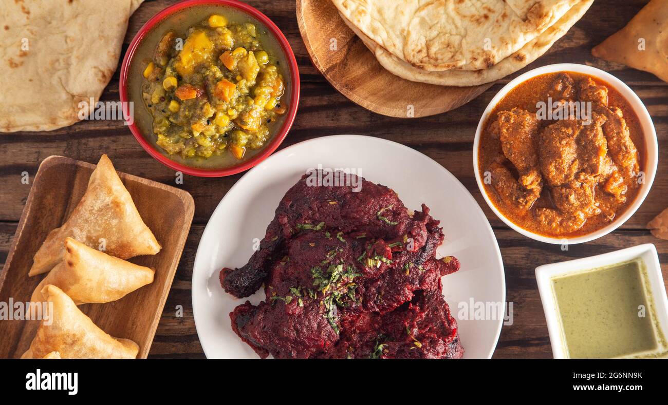 Tischset mit einem Abendessen aus verschiedenen Curry-Gerichten auf einem rustikalen Holztisch Stockfoto